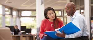 An advisor sits with a student and shows her a binder