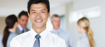 An asian business man smiling with coworkers in the background