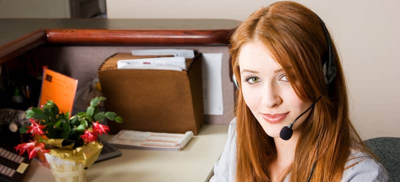 Redheaded woman at her desk on the phone.